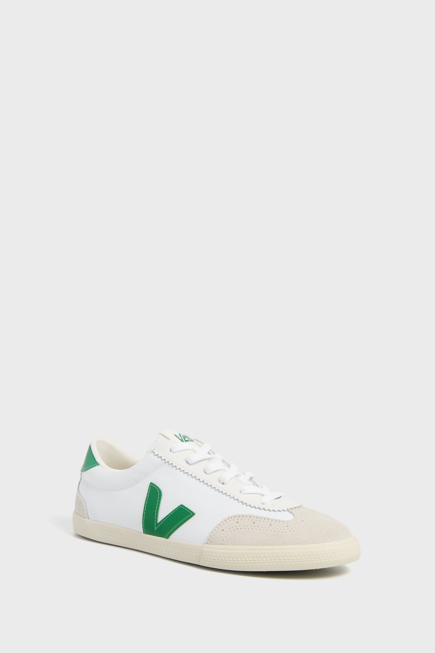 The VEJA sneaker features a white design with green accents, including a green V logo, white laces, and a beige toe cap. Made from sustainable materials.