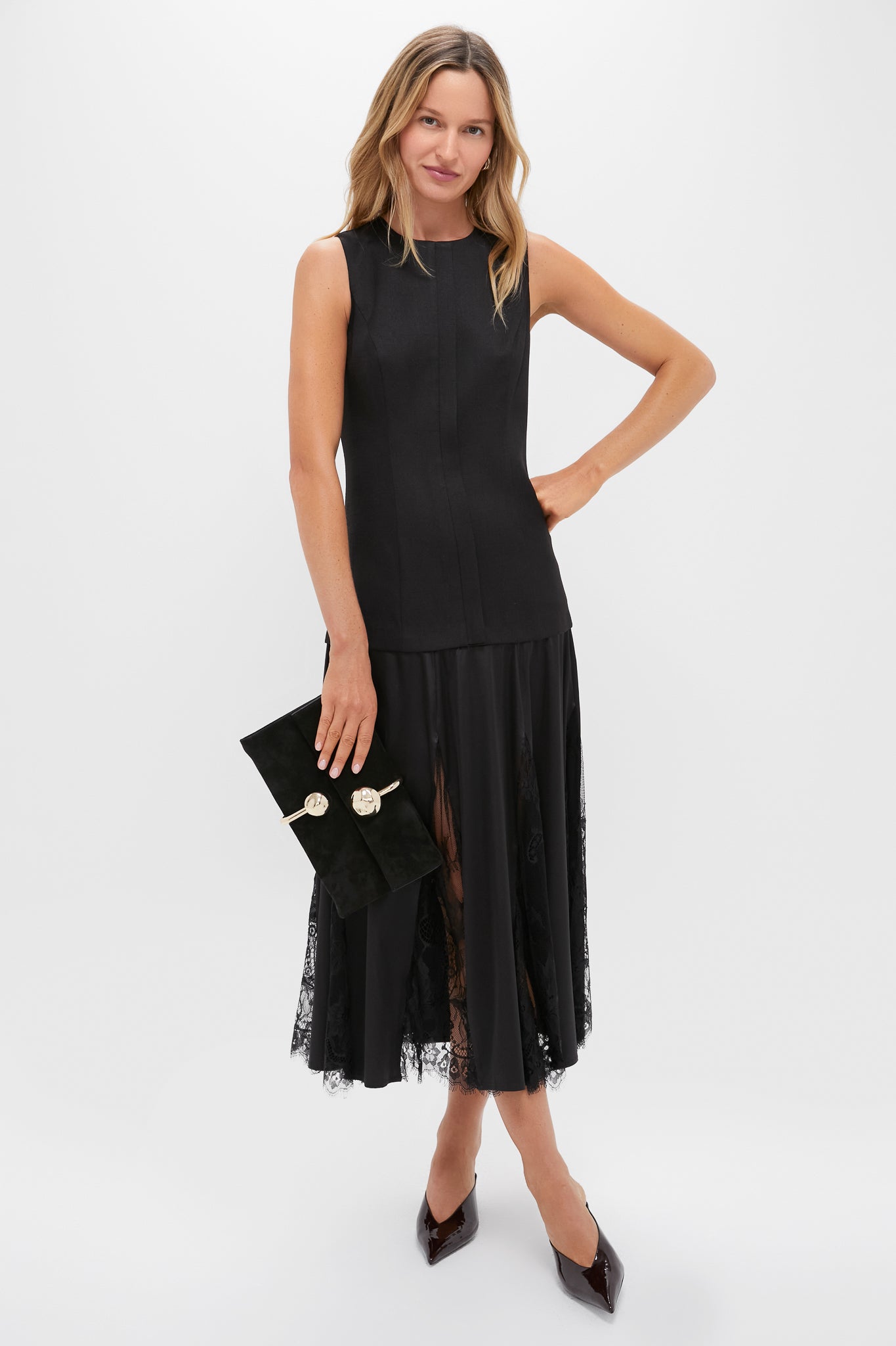 Model wearing the Black Mixed-Media Coco Maxi Dress, featuring a classic tunic-style bodice, lace-paneled pleats, and an effortless, high-end look with a suede clutch.