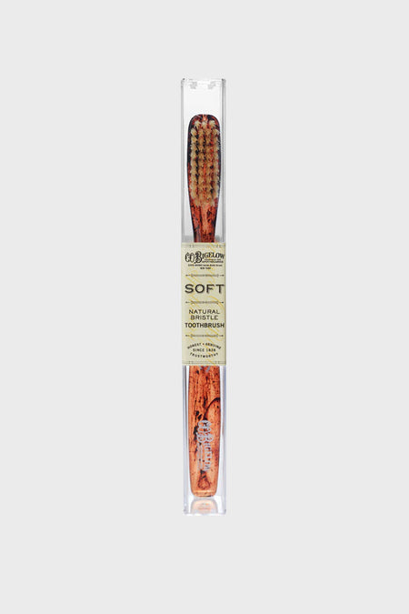 Soft Tortoise Natural Bristle Toothbrush by C.O. Bigelow, featuring classic wood-grain handle, effortless design, and high-end natural bristles in a clear travel sleeve.