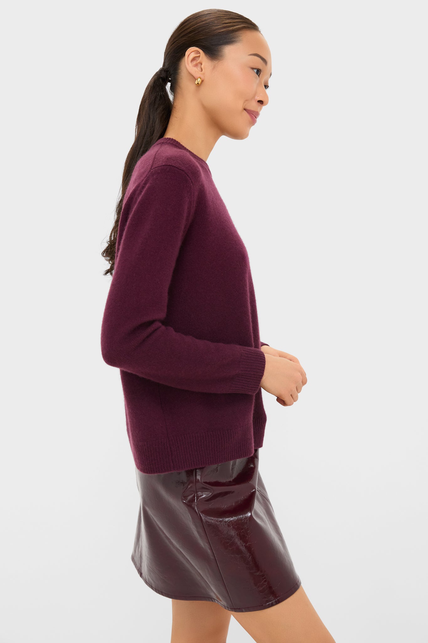 Woman in profile wearing Winetasting Cashmere Bodie Boyfriend Crewneck, showcasing a classic, effortless style with its luxurious, relaxed fit and ribbed hem, perfect for high-end, fun fashion.