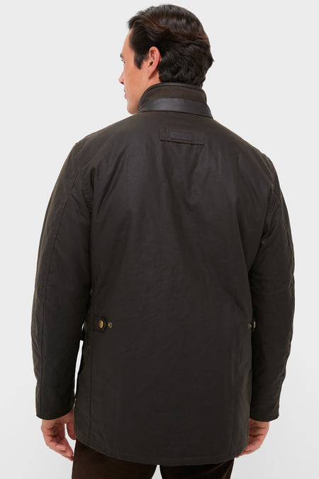 Back view of a man in a classic, high-end Olive Hereford Wax Jacket with leather trim, effortlessly showcasing Barbour’s timeless style and functional design against a light-gray backdrop.