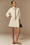 Young woman models the Winter White Embellished Nicola Dress, featuring a classic, jeweled collar and relaxed fit, styled with olive flats and a black clutch for an effortless, high-end look.