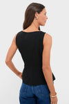 Woman wearing Black Sleeveless Decker Peplum Top with a classic scoop neckline and vertical seam detailing, styled effortlessly with high-waisted jeans and bold gold accessories.