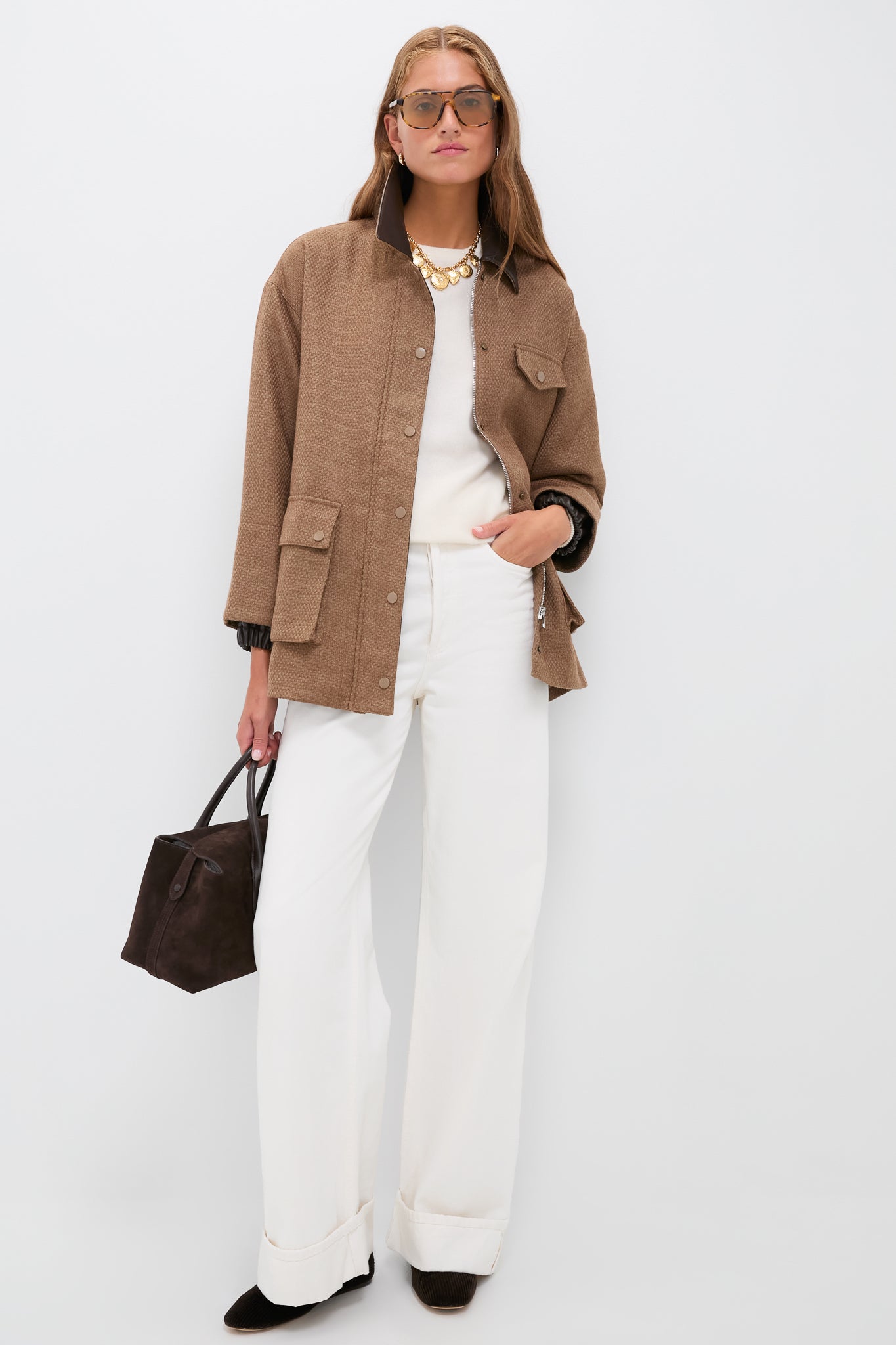 Woman in Brown Bourbon Jacket with snap-flap detailing, paired with white trousers and dark-brown accessories, exuding a classic, effortless, and high-end style.