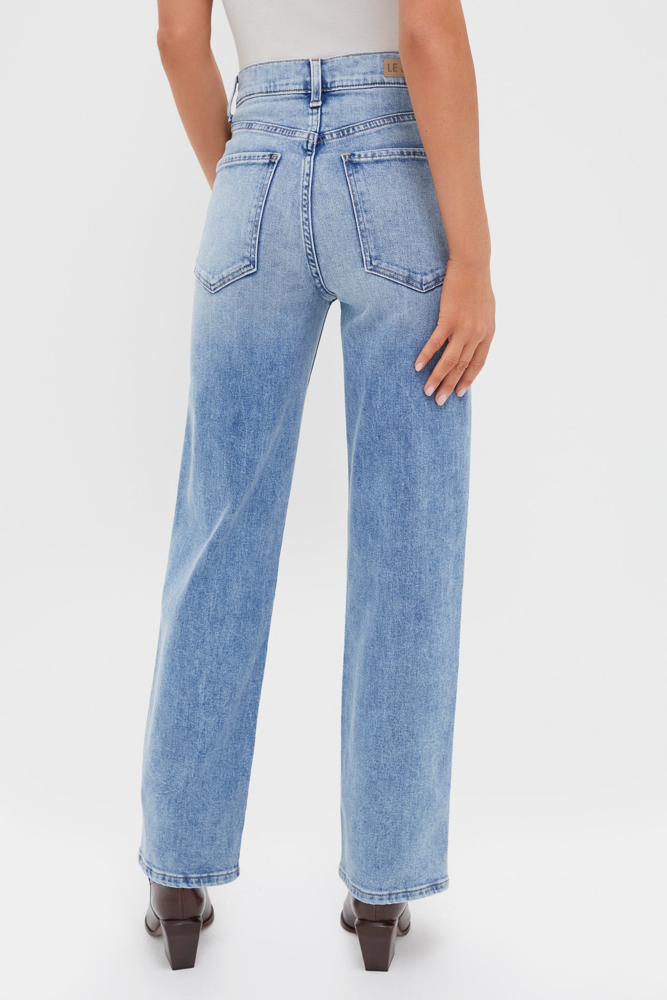 Model in classic, effortless LE JEAN Big Chill 90's Mid Rise Straight Ankle jeans, showcasing high-rise fit and clean hem, paired with high-end dark block-heel ankle boots.