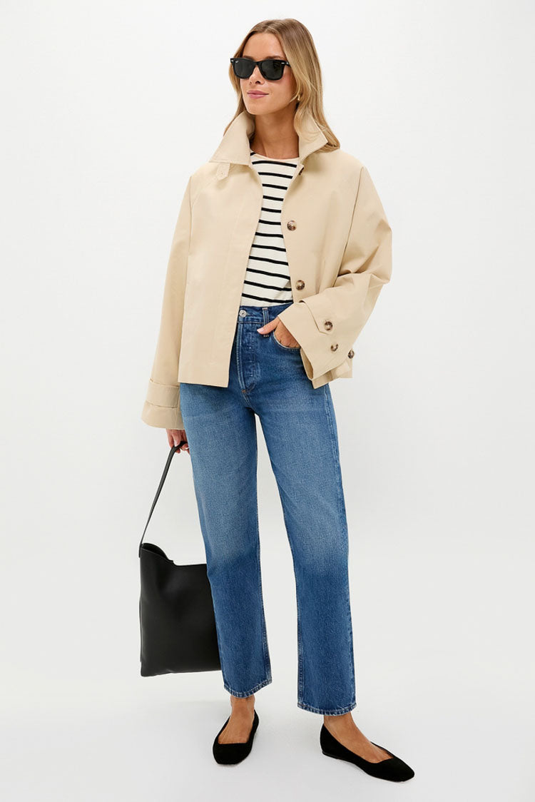 Person wearing classic Black Suede Nadia Flats with square toe, paired with a chic outfit of a beige jacket, striped top, blue jeans, and black tote, exuding effortless style.