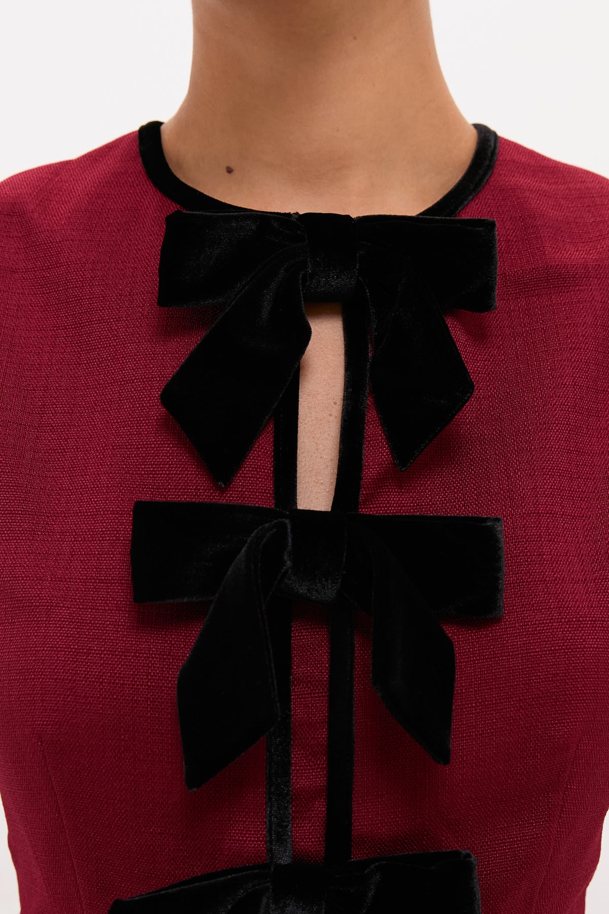 Cranberry Velvet Bow Jaclyn Mini Dress features classic black velvet bows, creating an effortless, fun, and high-end look with peekaboo details, embodying Tuckernuck's stylish charm.