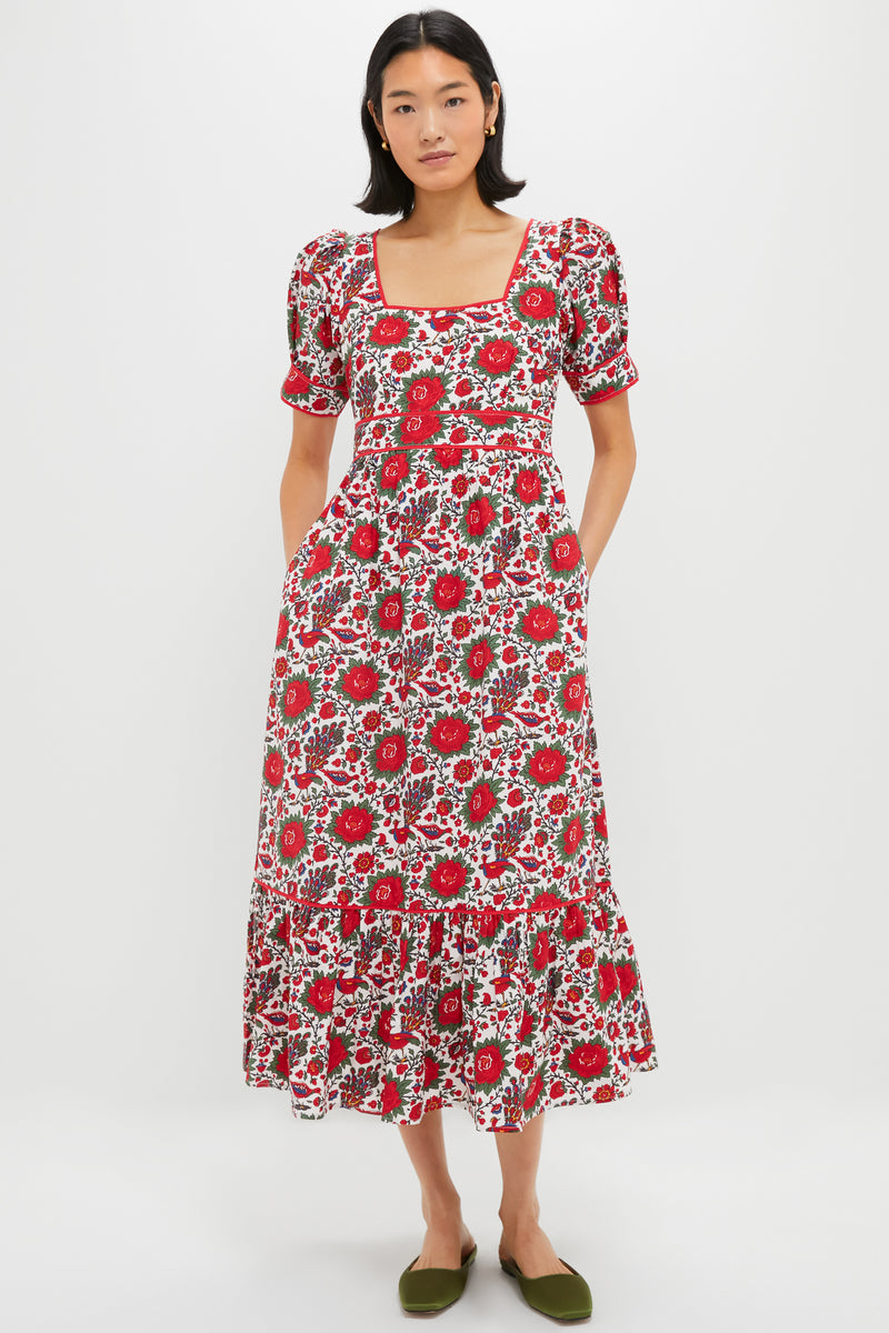 A woman wears a Pink City Prints red floral cotton poplin dress with short puff sleeves and a square neckline, paired with green flats.