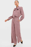 Fashion model in classic, high-end Mauve Stripe Wyatt Pants, wide-leg with banded waist, paired with matching Brianna Bow Blouse, embodying effortless, fun style.