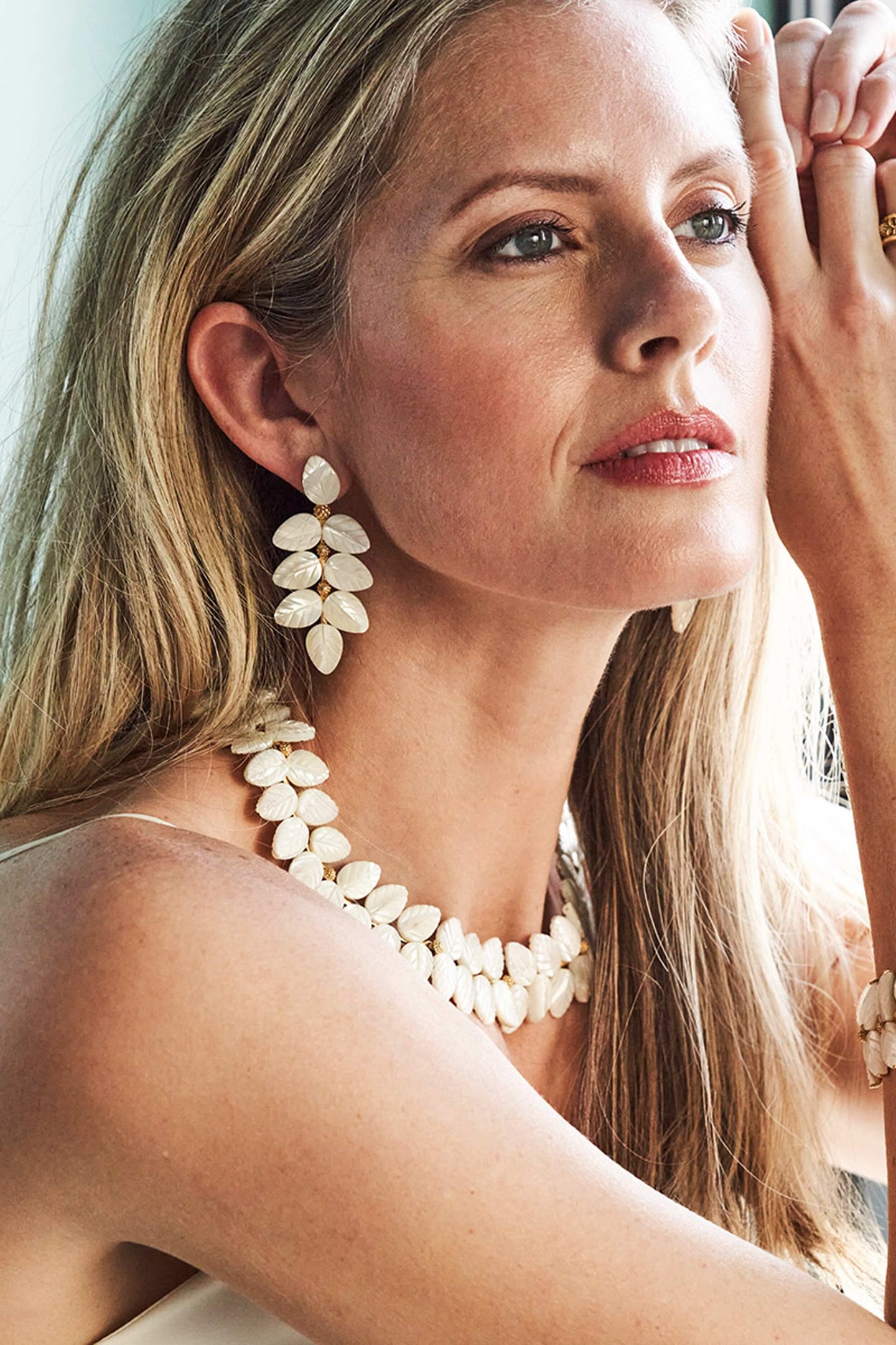 Blonde woman models Mermaid Garden Vine Drop Earrings - MOP, featuring classic, hand-carved mother of pearl leaves. She embodies an effortless, high-end, and fun style.