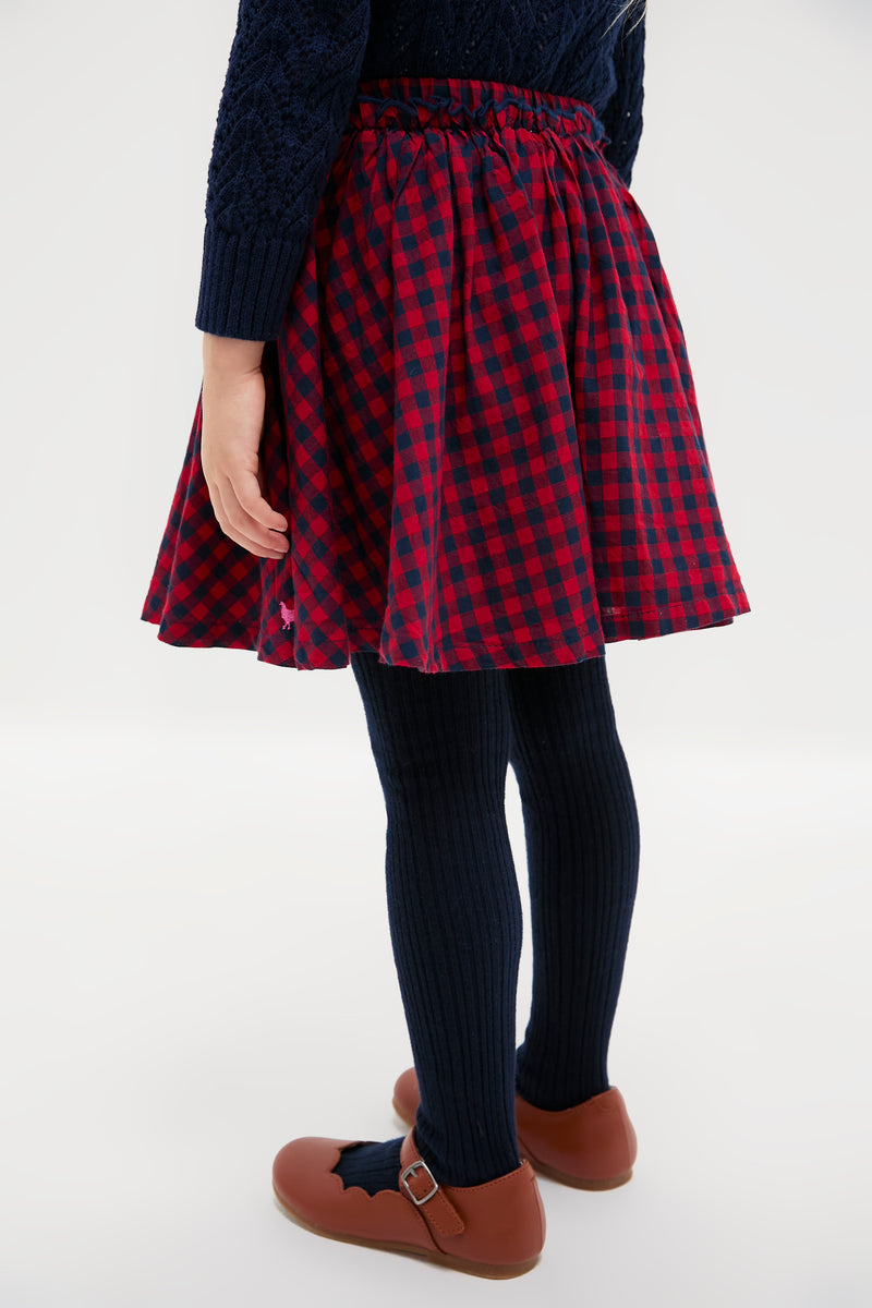 Child wearing the classic Red Blue Check Gianna Skirt with ruffle trim, paired effortlessly with navy tights and Mary Jane shoes, exuding a fun, high-end style.