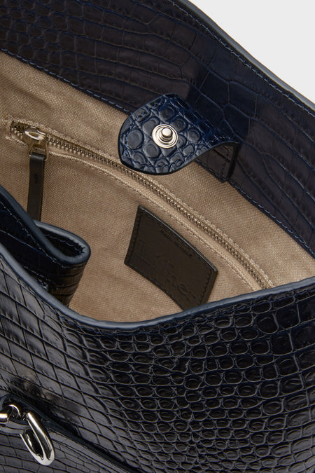 The Liffner blue croc-embossed bucket bag features Italian craftsmanship, a beige fabric interior, zippered pocket, adjustable shoulder strap, and a visible brand label.