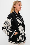 Woman in a high-end Black Cream Floral Arabesque Fleece Coat with a classic notched collar, oversized sleeves, and fun, effortless floral scalloped pattern detailing.