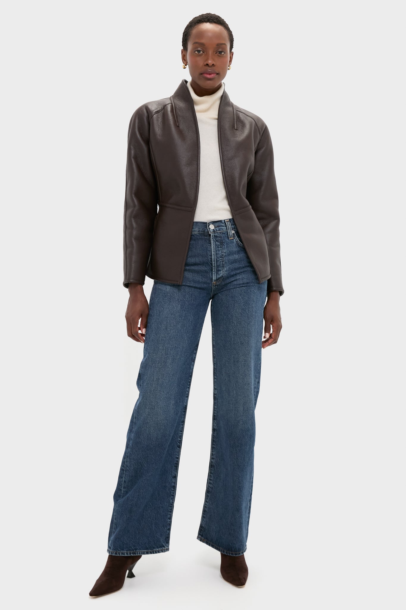 Model wearing an effortlessly classic Reversible Marron Fur Coat with faux leather, tied waist belt, and sherpa lining, styled with jeans and boots for a high-end look.