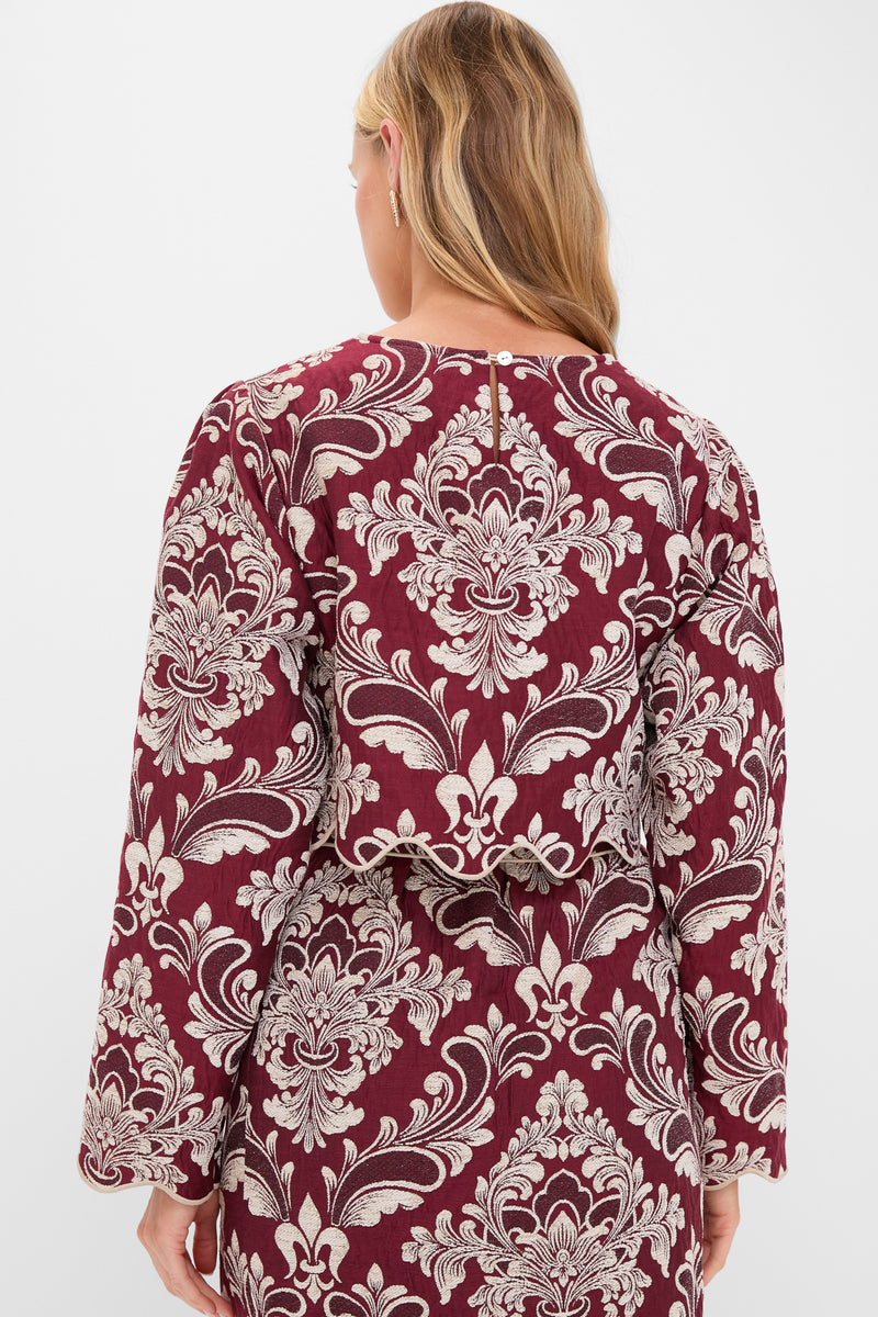Woman in Blush Pink and Burgundy Bicolor Jacquard Waves Long Sleeve Top, featuring classic baroque patterns and scalloped hem, embodies effortless, high-end style for fun, sophisticated occasions.