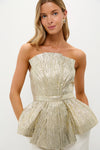 Model wearing Gold Plisse Iris Strapless Top: a classic, high-end peplum design in shimmering gold, offering an effortless, fun, and sculptural silhouette perfect for confident styling.