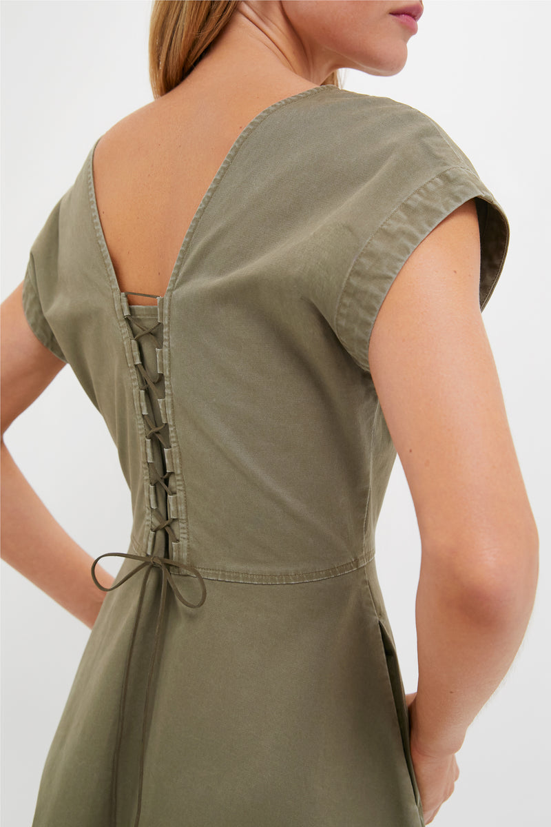 A person wearing the Tuckernuck Burnt Olive Chino Solen Midi Dress, with a V-shaped back and corset-style closure, is shown from the back and side.