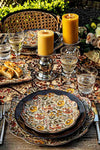 Ella Small Tumbler sparkles with classic elegance on a floral-patterned table, effortlessly enhancing any meal with its high-end, handcrafted design amidst a fun, garden-party setting.
