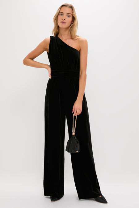 Model in a classic, effortless black velvet jumpsuit holds the high-end Black Rue Wristlet, a fun and glamorous evening bag with gold-tone chain straps.
