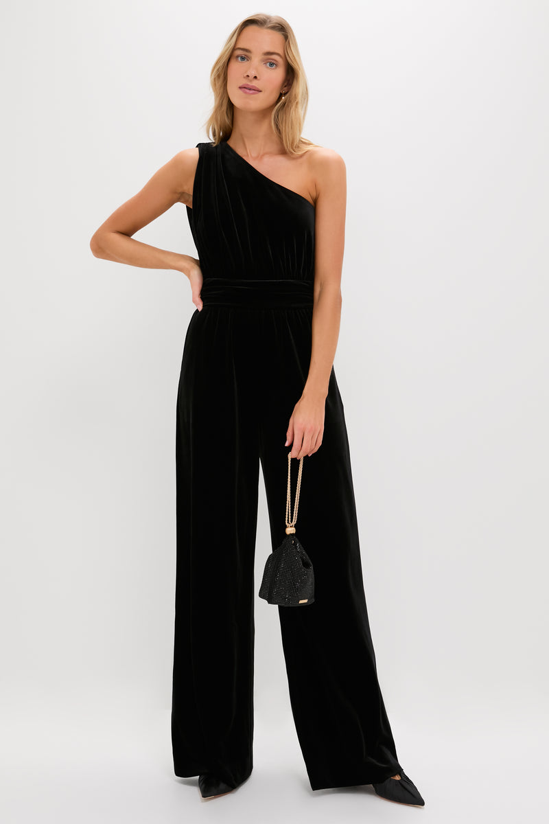 Model in a classic, effortless black velvet jumpsuit holds the high-end Black Rue Wristlet, a fun and glamorous evening bag with gold-tone chain straps.