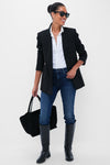 Woman in classic, effortless outfit featuring You're A Riot The Rascal Skimp jeans, styled with a blazer and boots, exuding fun and high-end confidence.