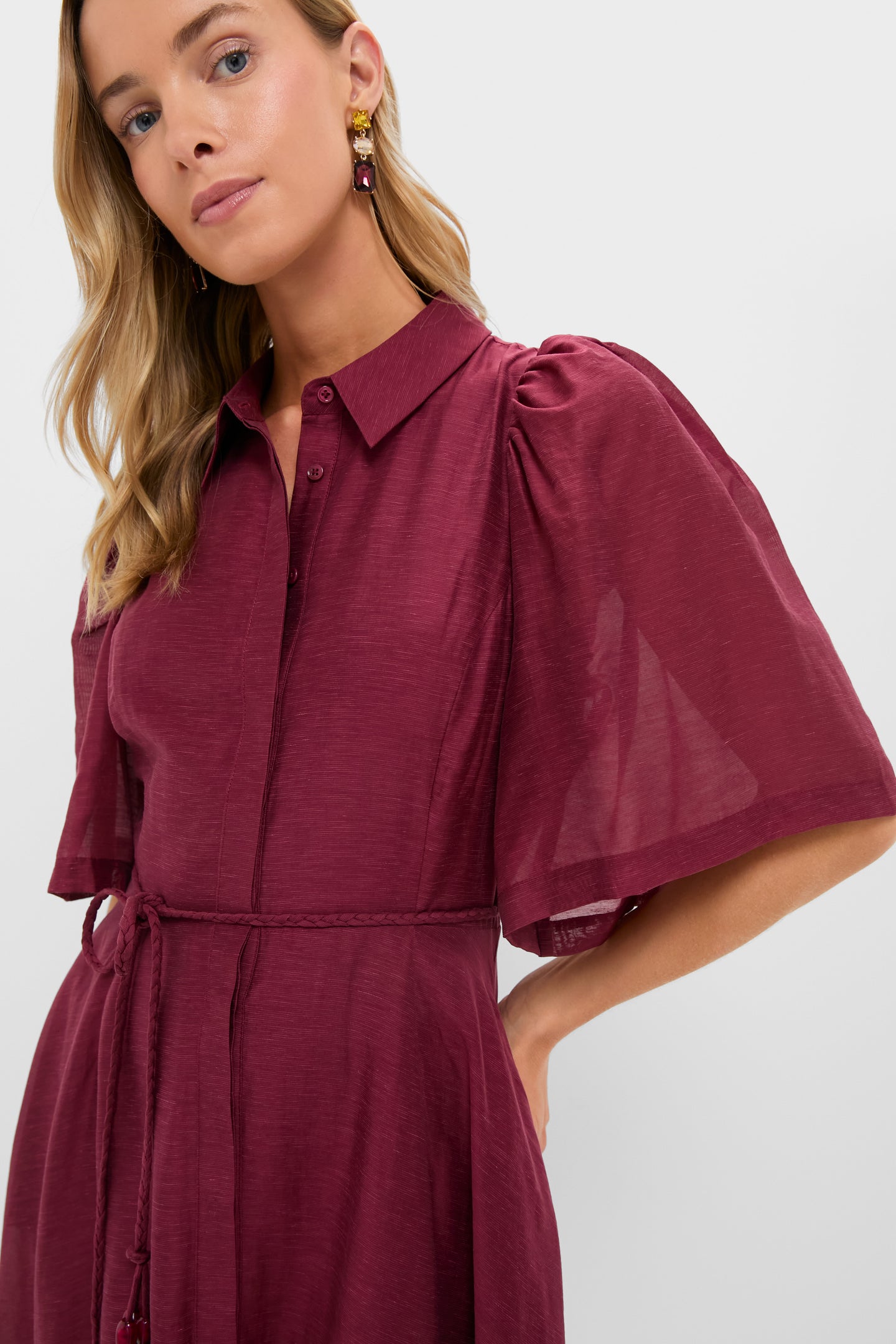 Woman wearing the classic Oxblood Cindy Midi Dress with elbow-length puff sleeves, a hidden-placket front, and a braided belt, exuding effortless, high-end style.