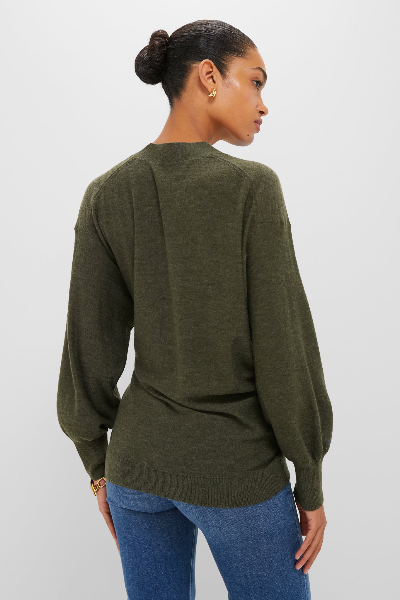 Woman modeling the Olive Drippy Tissue Cardigan, showcasing its classic, effortless style with ballooned sleeves and a cinched waist, paired with skinny jeans.