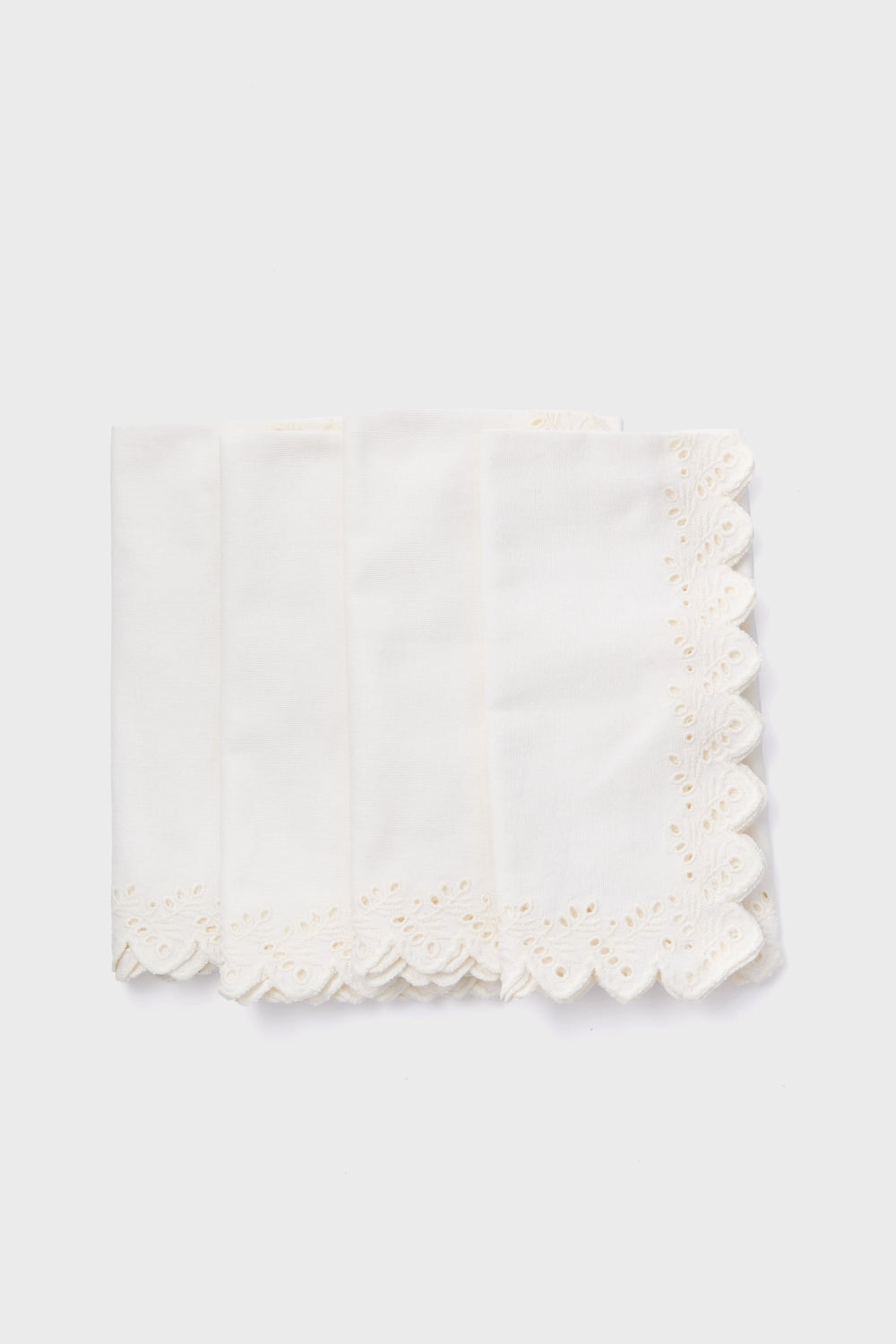 Tuckernuck Homes set of four white cotton napkins features scalloped, embroidered edges and arrives neatly stacked—a stylish tabletop addition.