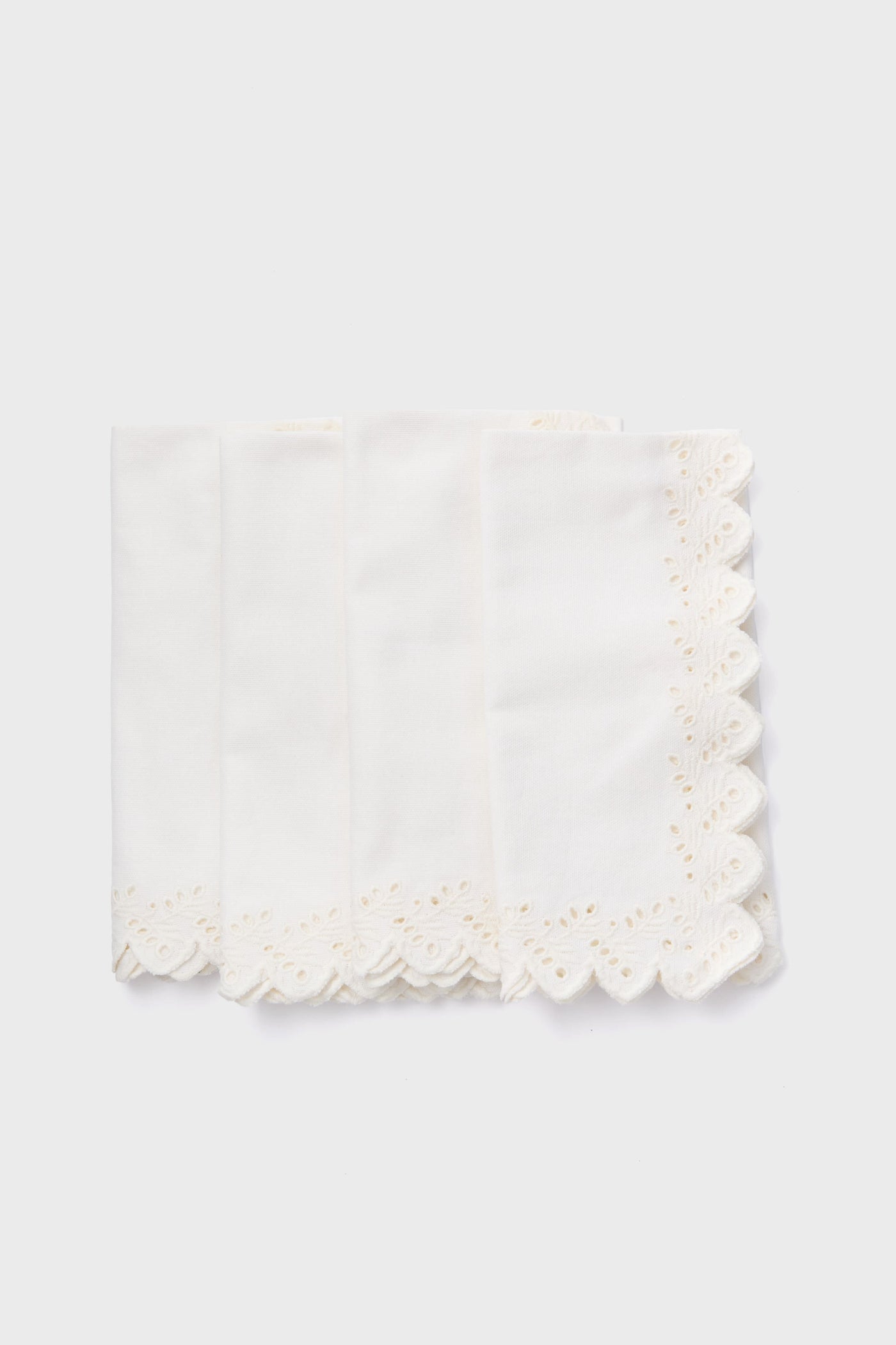 Tuckernuck Homes set of four white cotton napkins features scalloped, embroidered edges and arrives neatly stacked—a stylish tabletop addition.