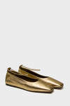Maria Luca gold metallic ballet flats with square toes and thin chain ankle straps, shown on a plain light gray background.