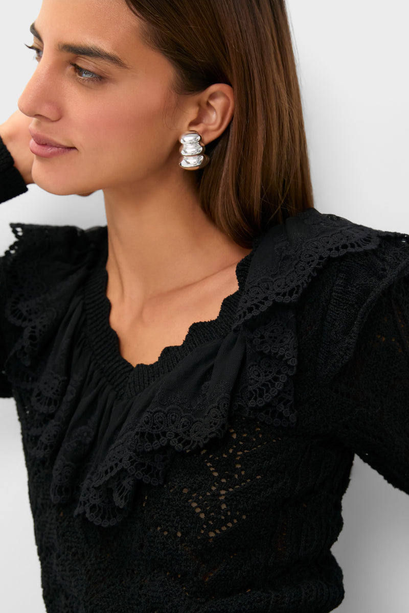 Woman wearing Black Pointelle Knit Sherry Top with scalloped ruffled neckline, showcasing chunky silver hoop earring, embodying classic, effortless style. Perfect for a fun, high-end look.