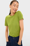 A woman stands with her hands in her pockets, wearing a green crewneck short sleeve slim fit top and dark blue jeans from Tuckernuck.