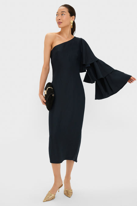 Model in Black Bidi Bidi Bom Bom Tea Length Dress with asymmetric neckline and dramatic sleeve, accessorized with gold earrings, black clutch, and gold heels for an effortless, high-end look.