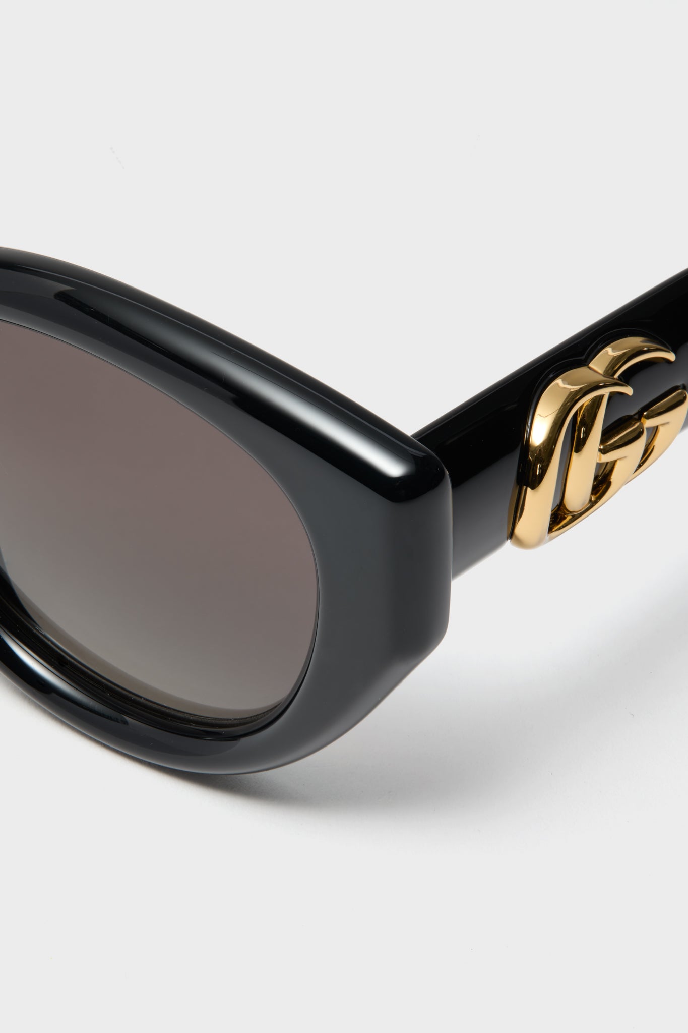 Shiny Black Cat-Eye GG Bag Sunglasses feature a classic acetate frame, dark gradient lenses, and Gucci's gold logo on the temples, offering effortless high-end style.