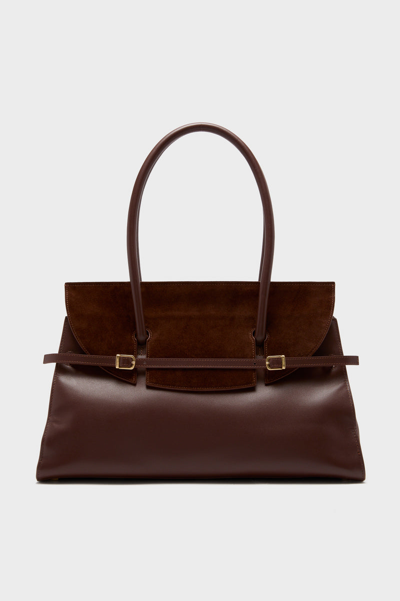 A structured rectangular handbag by SIMKHAI in dark brown leather and suede, featuring a suede flap, double handles, and gold-tone hardware.