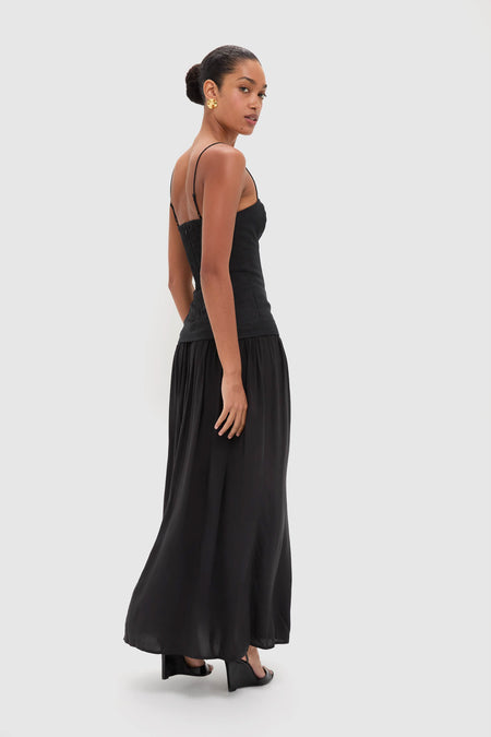 Model in classic Black Lenise Maxi Dress, showcasing an effortless, high-end look with a fitted bodice, flowing skirt, and adjustable straps, styled with fun heeled mules.