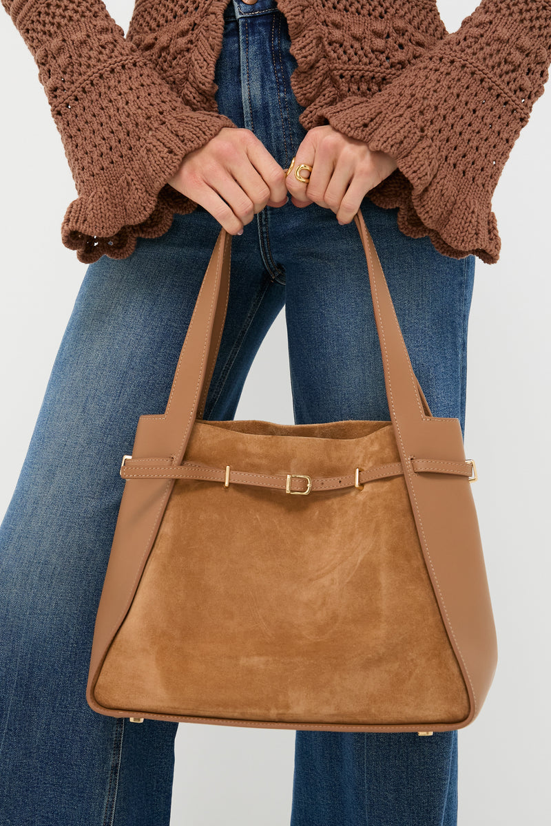 Camel Cleo Suede Tote, a classic high-end handbag with suede and leather contrast, held effortlessly, showcasing its elegant silhouette and fun, slim belt detail.