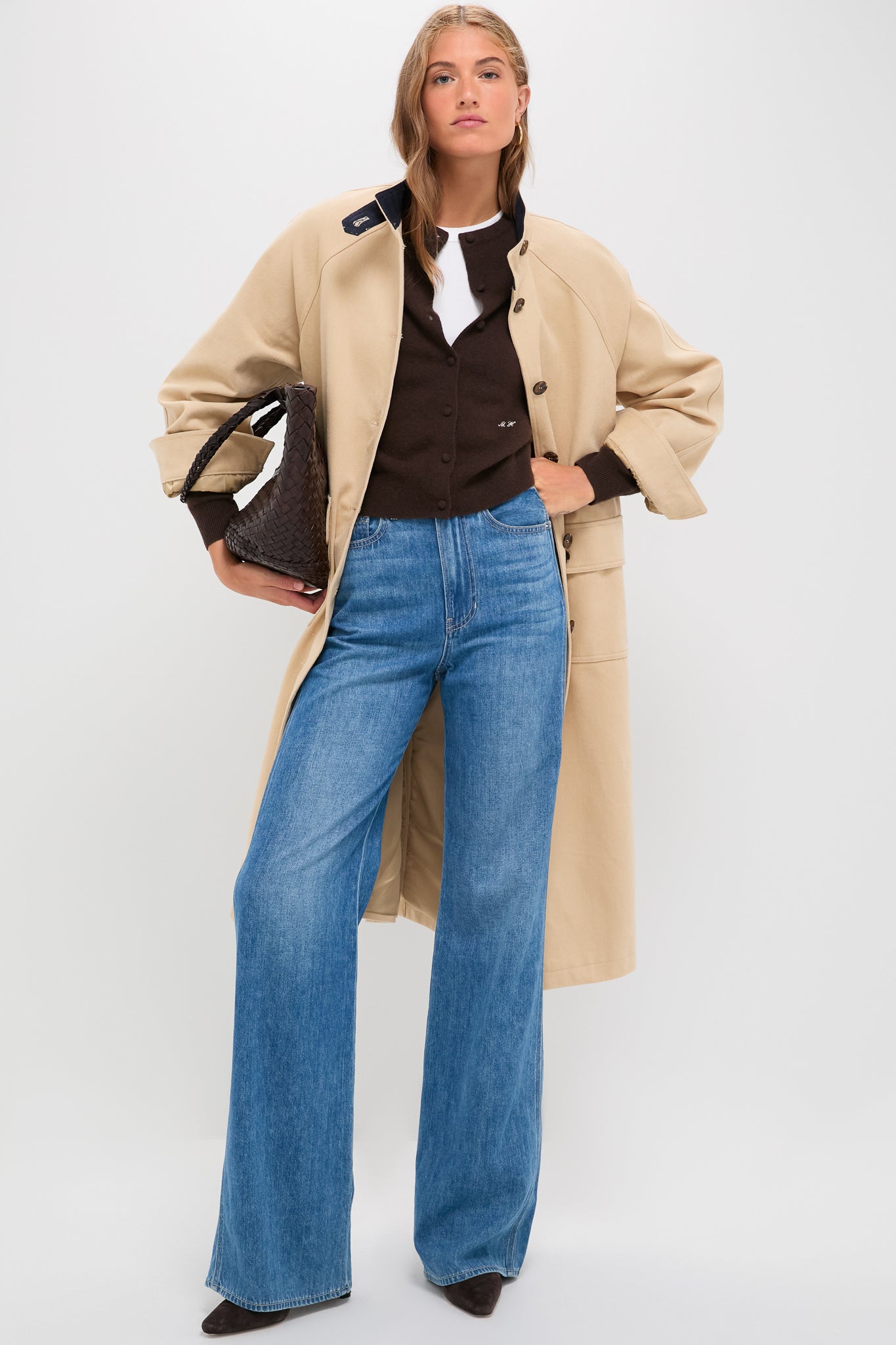 Model in a classic French Kiss Taylor High Rise Wide Leg jeans, styled effortlessly with a trench coat and woven tote, reflecting modern, high-end style.