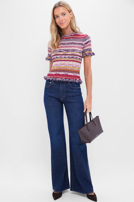 Model wearing Madison Kimberly 70's Flare jeans with high-waisted, wide-leg design, paired with a striped ribbed top and dark structured tote, exuding effortless, classic style.