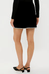 Black Velvet Rhinestone Loverly Mini Skirt with rhinestone trim, showcasing a chic, classic, and fun design, paired with black slingback heels for an effortless, high-end look.