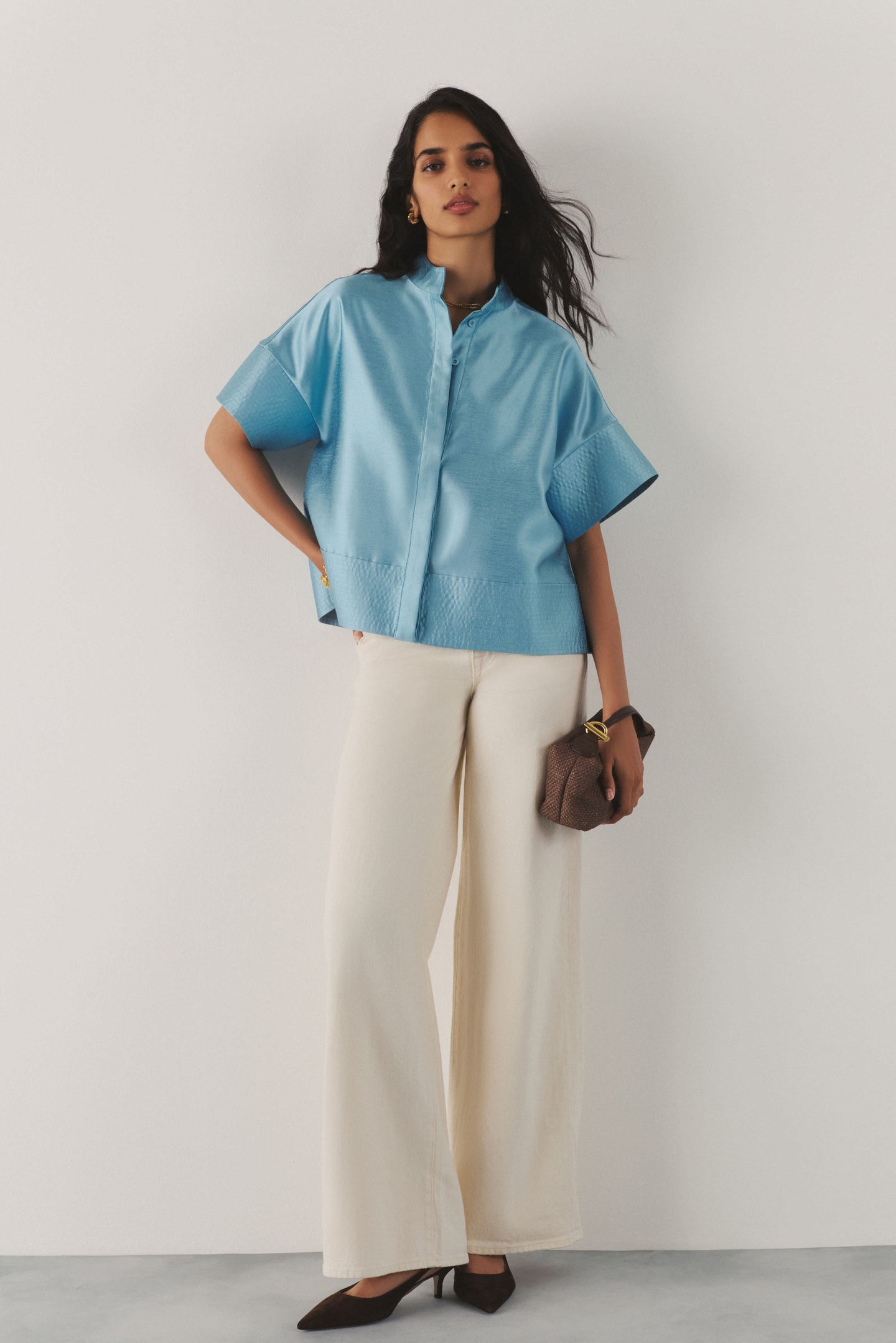 Woman in a blue top and cream pants. 