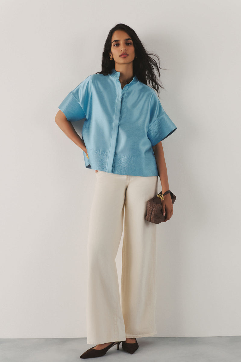 Woman in a blue top and cream pants. 