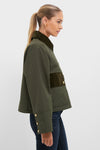 A woman in side profile wears the Barbour Olive Phoebe Casual Jacket with a dark green corduroy collar and accents, paired with dark blue jeans, against a plain background.