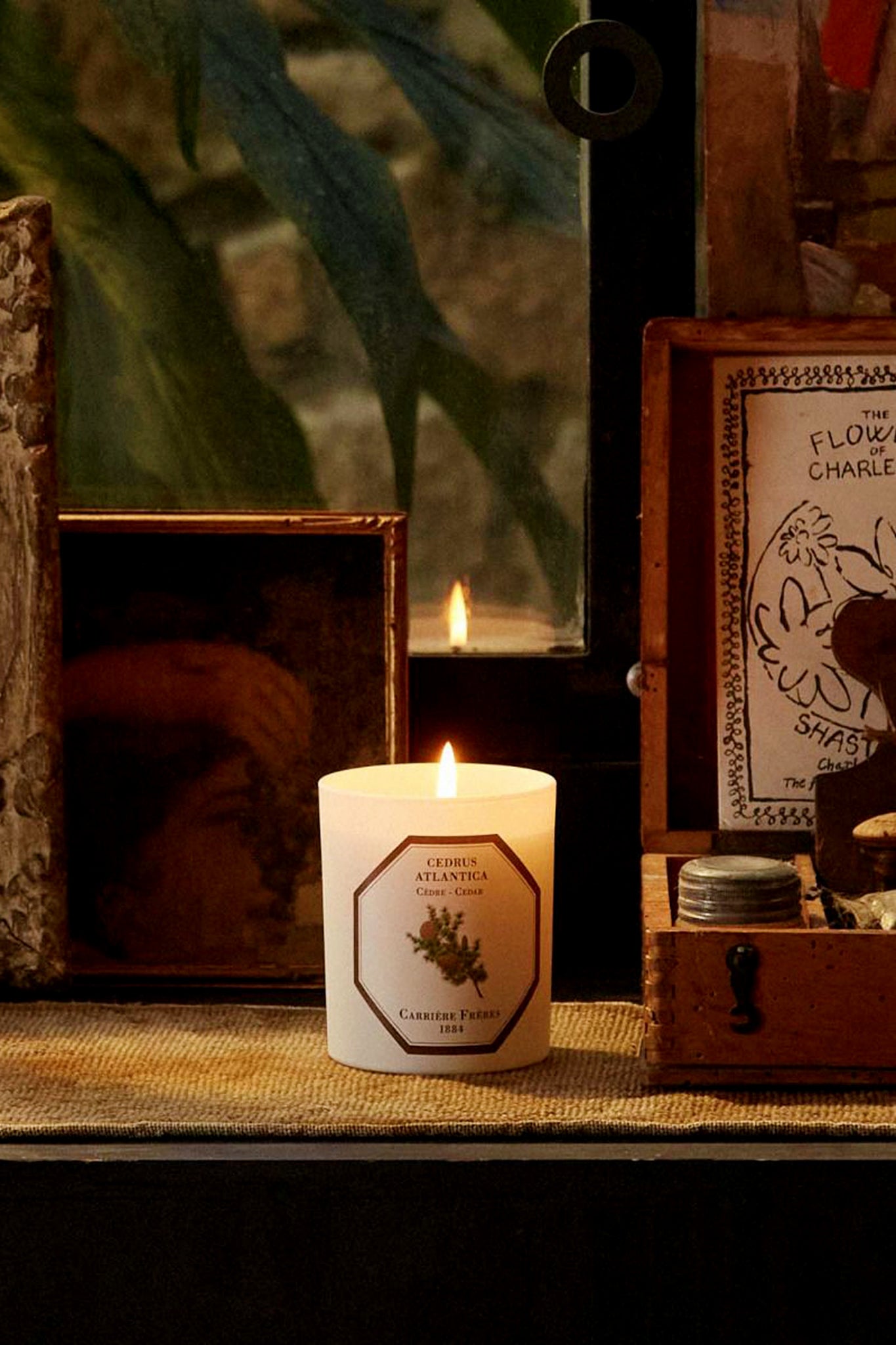 Cedar Candle by Carrière Frères, elegantly lit on a woven mat, exudes classic, effortless warmth. Perfect for gifting, its high-end, woody fragrance offers 40+ hours of burn time.