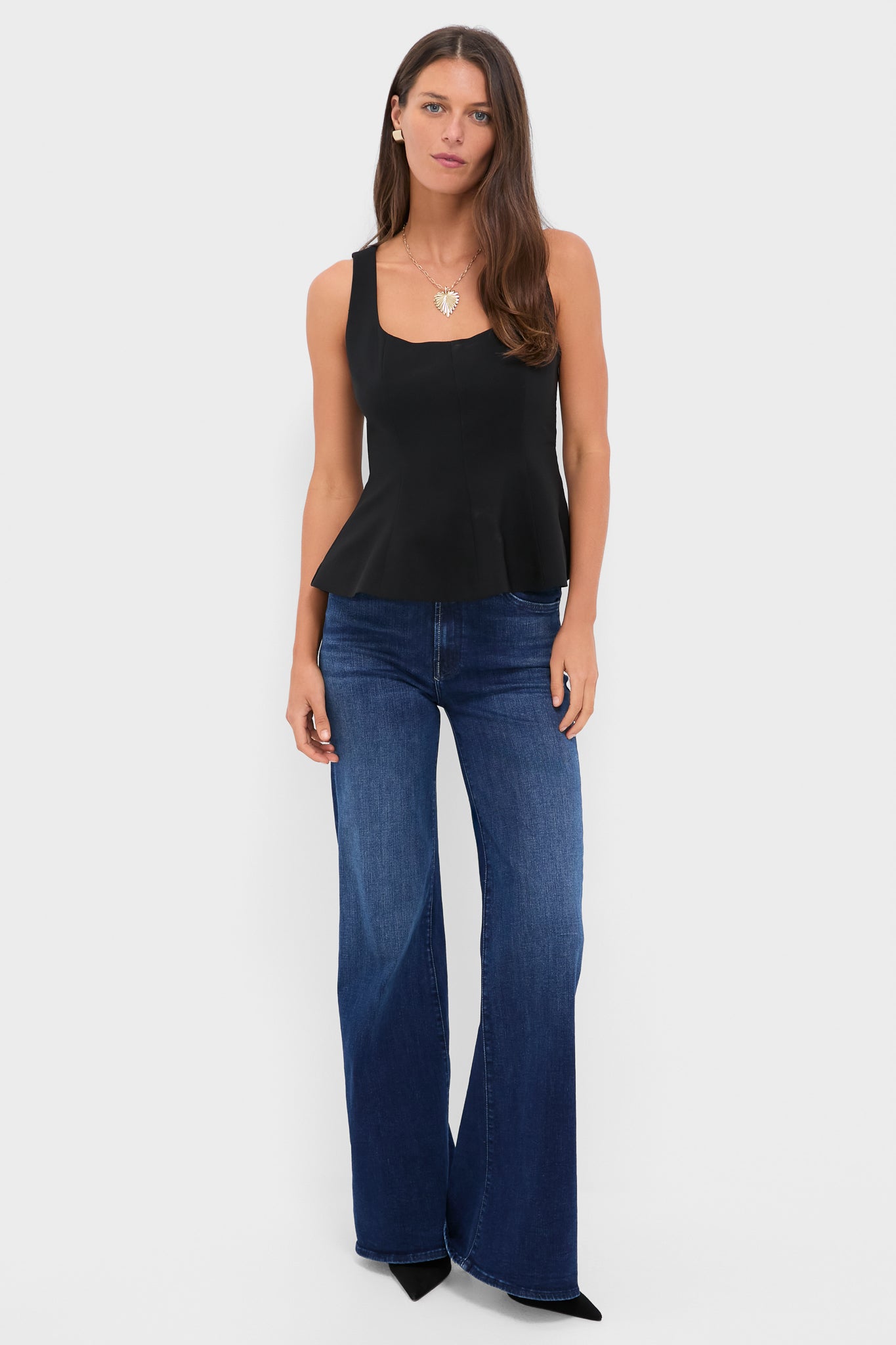 Model wearing the Black Sleeveless Decker Peplum Top, a classic and effortless piece with a scoop neckline and side zip, paired with high-end jeans.