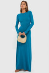 Woman in a classic, effortless Nocturnal Blue Dora Long Sleeve Maxi Dress, holding a woven handbag, styled with hoop earrings and sandals, reflecting a high-end, fun aesthetic.