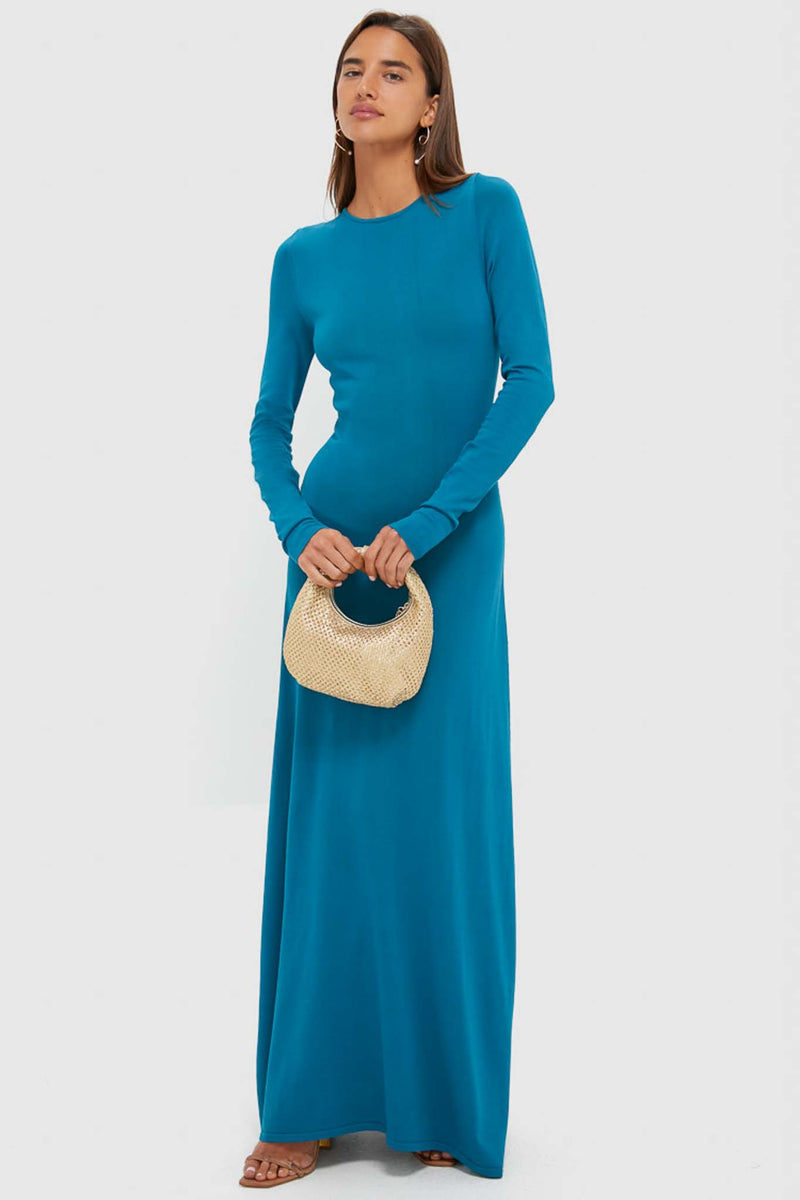 Woman in a classic, effortless Nocturnal Blue Dora Long Sleeve Maxi Dress, holding a woven handbag, styled with hoop earrings and sandals, reflecting a high-end, fun aesthetic.