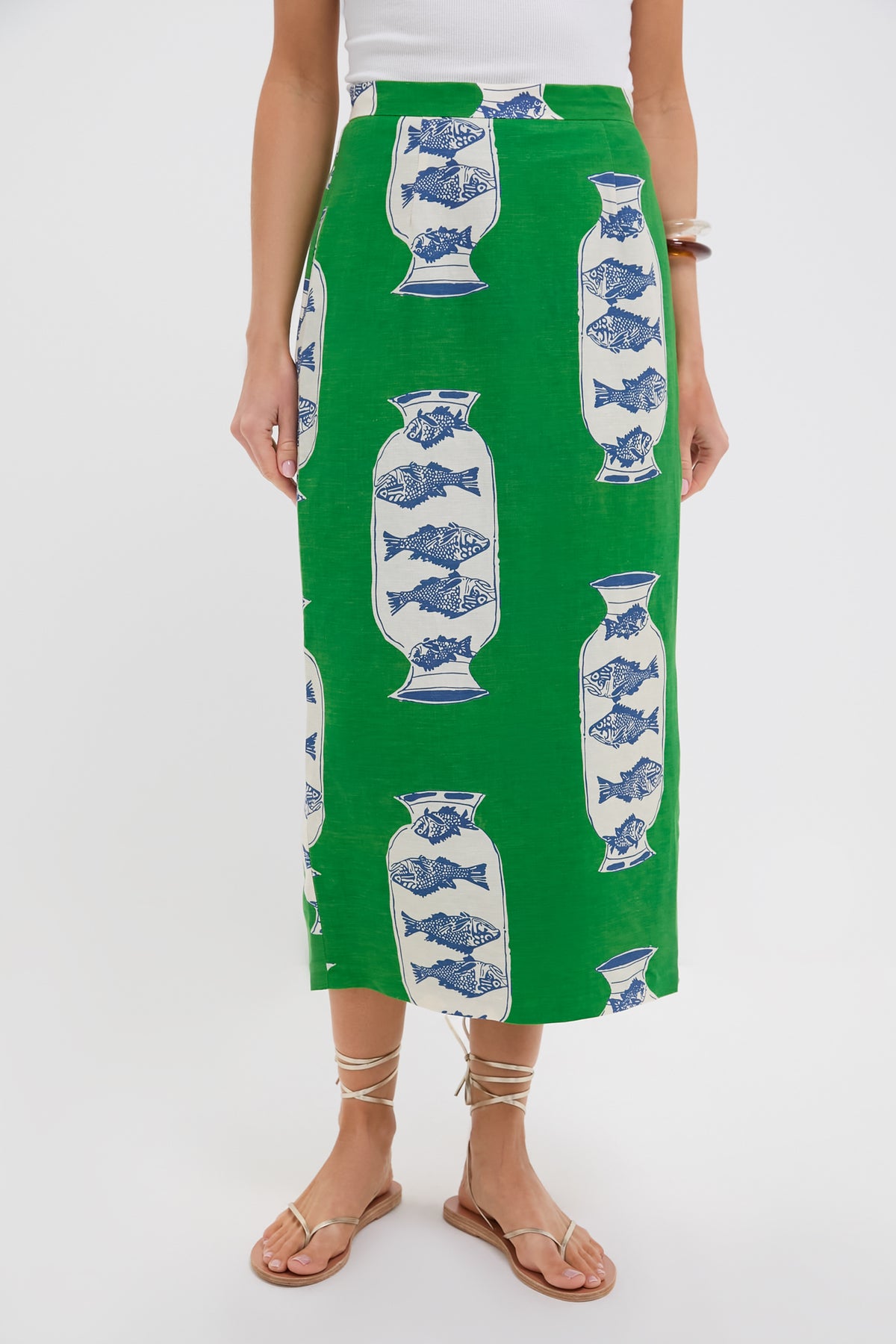 Wearing a Hunter Bell Herring Green linen-blend Isla Skirt with a blue and white vase pattern, paired with a white top and flat strappy sandals.