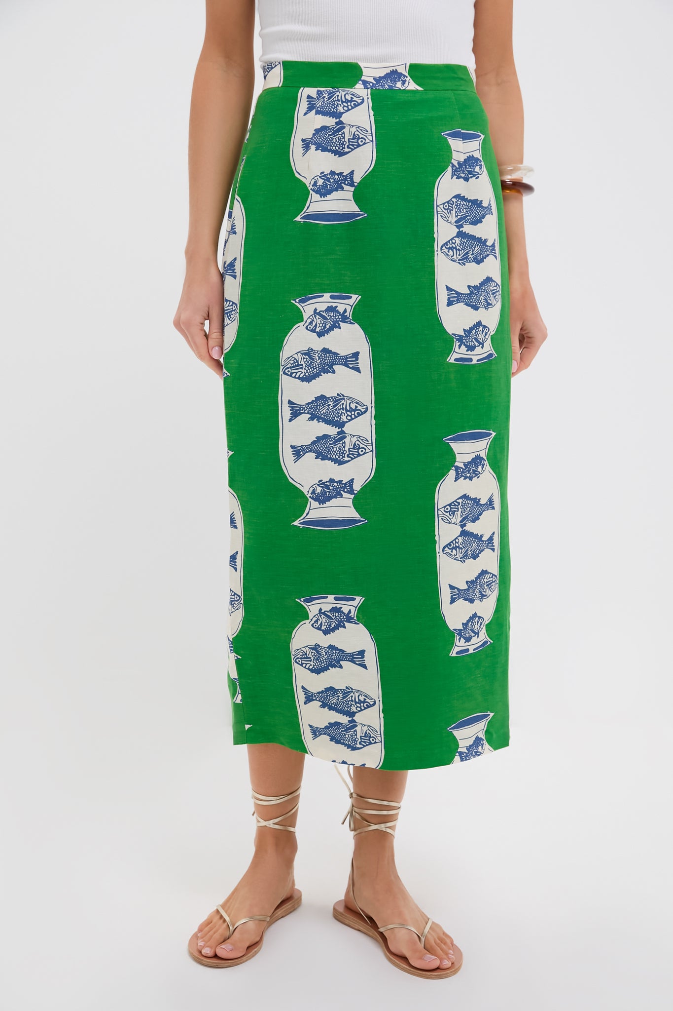 Wearing a Hunter Bell Herring Green linen-blend Isla Skirt with a blue and white vase pattern, paired with a white top and flat strappy sandals.