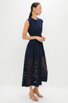 Woman in profile wearing the Navy Astrid Midi Dress, featuring a classic sleeveless design, fitted waist, flared skirt with laser-cut detailing, styled with effortless elegance and fun, high-end accessories.